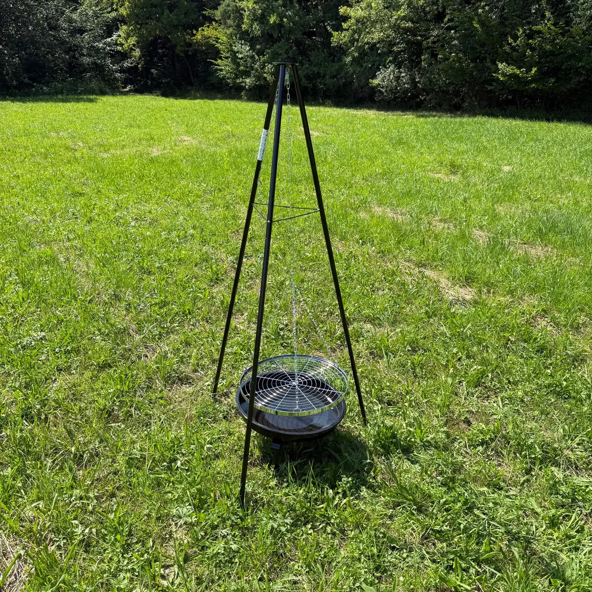 Grill na trójnogu Hefajstos z misą i rusztem na trawie w słoneczny dzień